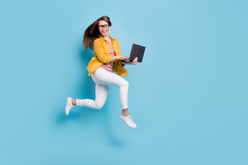 Wall Mural - Full body profile side photo of young woman happy positive smile jump up go run hold laptop isolated over blue color background