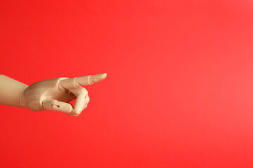 Wall Mural - Wooden mannequin hand on red background. Space for text