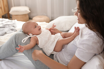 Canvas Print - Happy young mother with her cute baby on bed at home