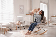 Happy Young Mother With Her Cute Baby In Rocking Chair At Home