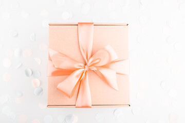 present gift box with pink bow with festive confetti. Birthday, weeding, Christmas holiday and congratulation concept. Flat lay style.