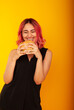 © Marina Chernivetskay - a girl with pink hair of European appearance looks at the burger biting her tongue licking wants to eat it