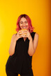 © Marina Chernivetskay - a girl with pink hair of European appearance looks at the burger biting her tongue licking wants to eat it