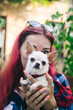 © Siniehina - The girl holds a mini chihuahua in her arms. Kissing your pet. The dog and the owner are dressed in the same color. Clothes for animals. Love and care for four-legged pets.