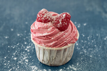 Sticker - Closeup shot of a tasty strawberry cupcake with raspberries on a blue surface