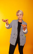 © Marina Chernivetskay - a girl of American appearance with two pizzas in her hands on a yellow background advertising fast food