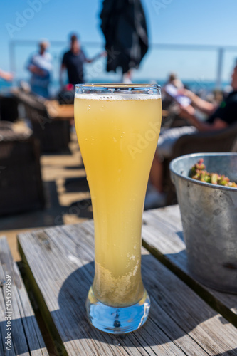 Glass of non-alcoholic white beer served outdoor on terrace with sea view