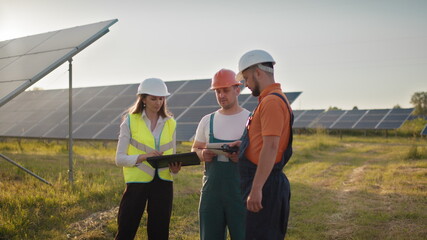 three solar energy specialists at a solar power facility. professional engineers discuss innovative 