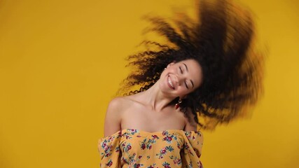 Wall Mural - Charming overjoyed excited jubilant exultant young latin curly woman 20s wears casual flower dress dance waving fooling around have fun enjoy play fluttering hair isolated on plain yellow background