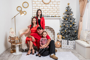 Hermosa familia en su casa posando para la foto navideña con ropa roja y adornos blancos y dorados