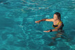 © Vit-Vit - A young woman in clear water in a water park. A young woman at the water park on a sunny summer day outdoors. Summer active recreation.