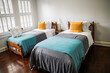 © Ursula Page - A guest bedroom with two twin beds with turquoise and gray bedspreads and yellow decorative pillows