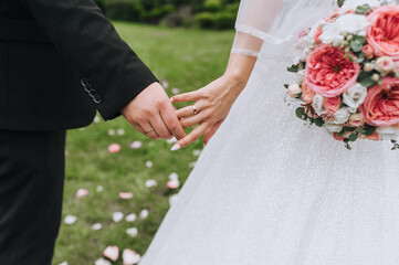 Wall Mural - Hands of the newlyweds with gold rings on the fingers and a bouquet in hand close-up. Wedding photography.