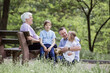 © Andrey Bandurenko - Three generation family in park: grandfather sitting on bench, father, and grandchildren