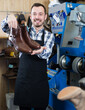 Ordinary worker displaying result of his work in shoe repair workshop
