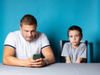 © Виталий Сова - Home lessons with the child, dad is distracted by the phone while the son is bored and waiting for his attention
