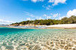 (Selective focus) Split-shot, over-under shot. Half underwater half sky with turquoise sea and a white sand beach with green vegetation. Liscia Ruja, Sardinia, Italy.