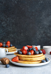 Canvas Print - Homemade pancakes with strawberries and blueberries for breakfast on the kitchen table.