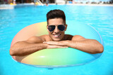 Fototapeta  - Young man with inflatable ring in swimming pool