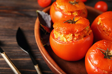 Plate with tasty stuffed tomatoes on wooden background, closeup