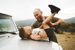 © fotofabrika - Dad and son playing on the hood of a car on road trip