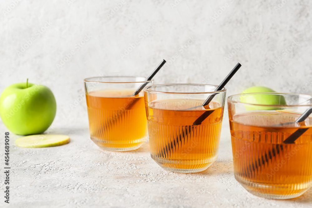 Glasses of apple juice on light background