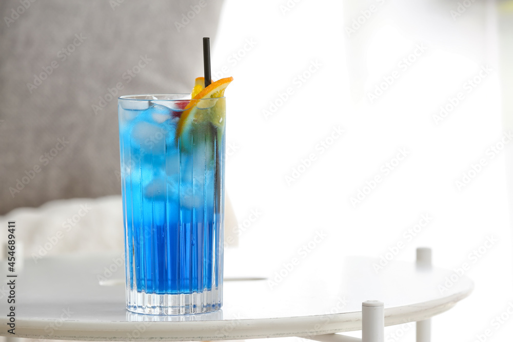 Glass of Blue Lagoon cocktail on table in room