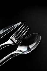 Transparent plastic fork, spoon and knife isolated on black background. 