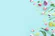 © tomertu - Top view image of pink, yellow and purple flowers composition over pastel blue background .Flat lay