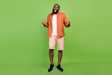 Wall Mural - Full body photo of optimistic millennial brunet guy sing wear shirt shorts shoes isolated on green background