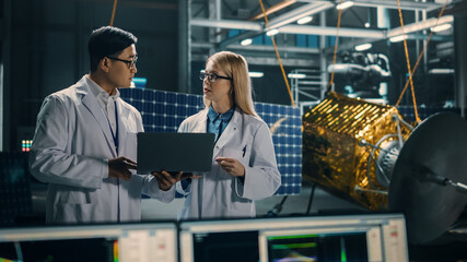 Engineer and Technician Working on Satellite Construction. Aerospace Agency: Diverse Team of Scientists Using Technological Equipment and Laptop Computer to Develop Spacecraft for Space Exploration.