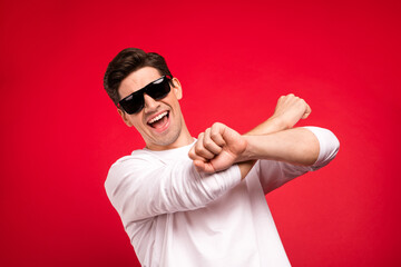 Canvas Print - Photo portrait brunet guy in casual outfit wearing sunglass chilling on holidays dancing isolated vibrant red color background