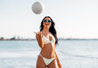 © Syda Productions - people, summer and leisure concept - happy smiling young woman in bikini swimsuit playing with volleyball on beach