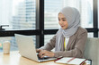 © amorn - Asian Muslim business woman in hijab headscarf working with computer laptop in the modern office. business people, diversity and office concept