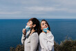 © Eva - two caucasian women outdoors removing face mask, breathing and keeping social distance in Pandemic during corona virus. Nature and mountain