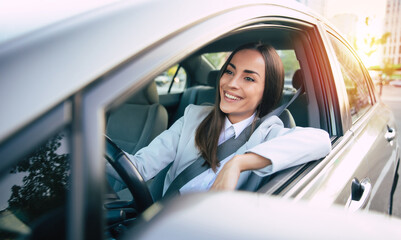 Portrait of cute female driver steering car with safety belt