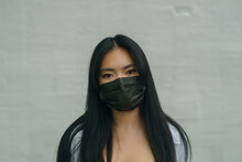 Portrait Of Asian Woman With Dark Hair Wearing Black Face Mask Against Air Pollution And Coronavirus Covid19, Looking At Camera