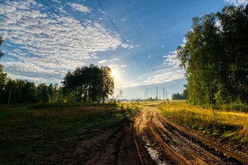 Wall Mural - The rising sun illuminates the dirt road leading to the village