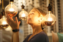 Side View Of Woman Touching Glowing Light Bulb