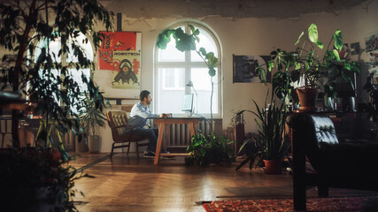 Aufkleber - Young Handsome Man Works on a Desktop Computer in Creative Agency in Authentic Loft Office. Renovated Stylish Decor with House Plants, Artistic Posters and Big Rounded Windows.