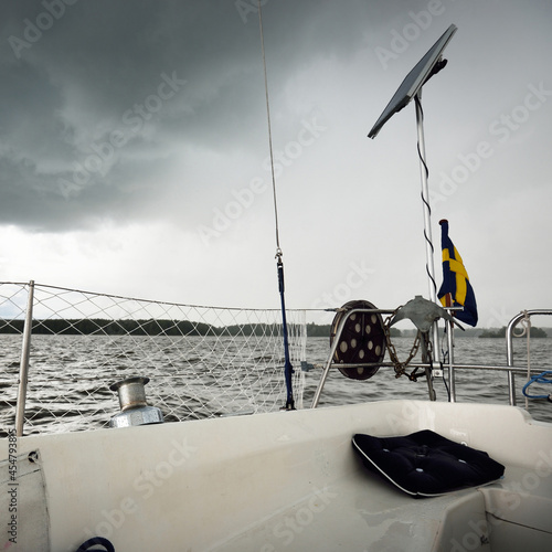 White yacht sailing during the storm. Boat side railing, mast winch, rigging equipment. 32 feet swedish built cruising sailboat. Mälaren lake, Sweden. Summer vacations, recreation, leisure activity