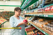 © Zuev Ali - An elderly woman chooses fruits in the store. Grandma in the fruit section of the supermarket.