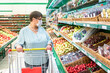 © Zuev Ali - A grandmother wearing a medical mask and a shopping trolley selects products in the store.