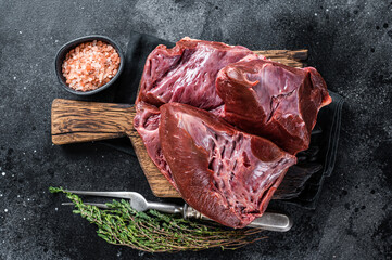 Wall Mural - Raw cutted Beef or veal heart on a butcher board. Black background. Top View