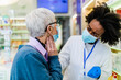© hedgehog94 - Professional Black female pharmacist talking with senior customer in modern drugstore. They are wearing face protective masks for protection from Coronavirus.