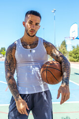 Wall Mural - Vertical shot of a sporty Caucasian male with tattoos playing basketball