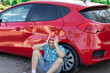 a young man sits upset near his car with a dent after an accident