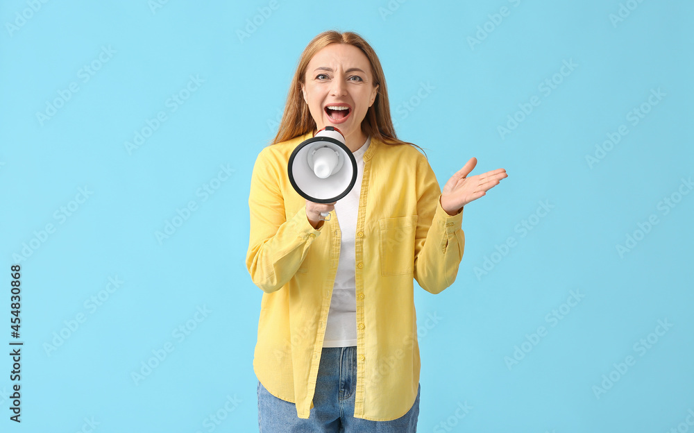 Mature woman shouting into megaphone on color background