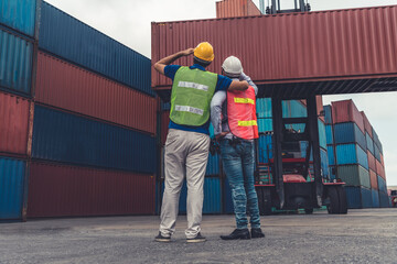 Wall Mural - Industrial worker works with co-worker at overseas shipping container yard . Logistics supply chain management and international goods export concept .