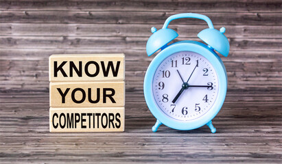 Wall Mural - the text know your competitors is written on wooden blocks and on a wooden background with an alarm 
